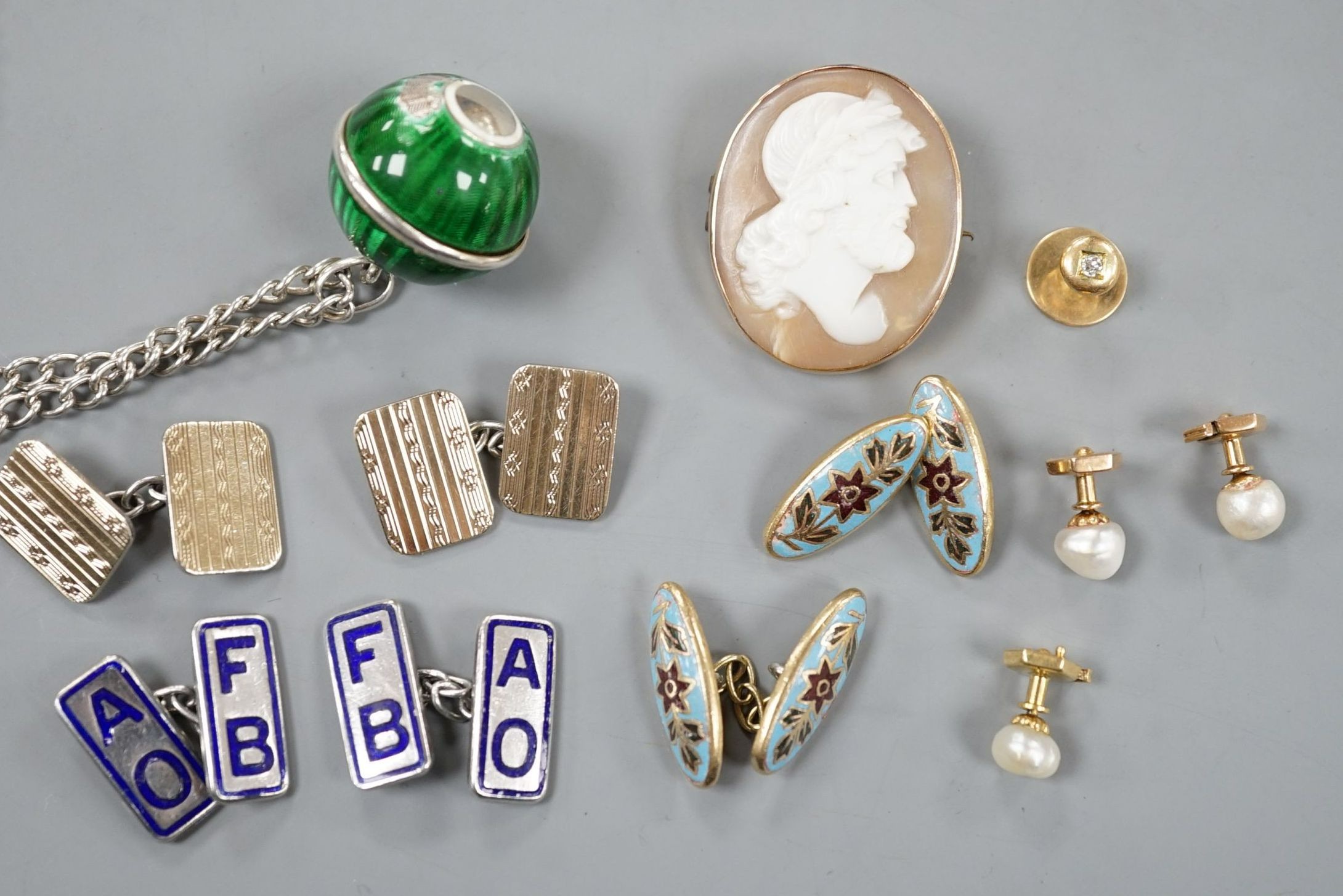 An early 20th century French white and yellow metal, green enamel(a.f.) set pomander, 19mm, on a white metal chain, three French (18ct poincon mark) and baroque pearl set dress studs, gross 3.5 grams, a diamond set 15ct